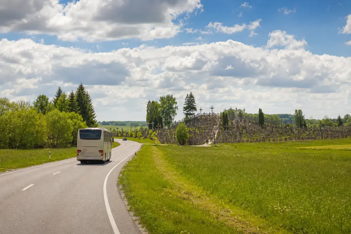 Private coach approaching Lithuania’s Hill of Crosses through the spring countryside.