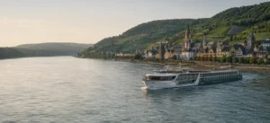 Modern river-cruise ship sailing past a historic European riverside town