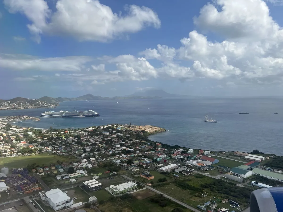 Aerial view over Basseterre and Port Zante, with cruise ships at the pier and the St. Kitts coastline extending toward Nevis.
