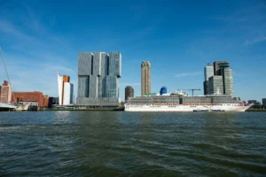 Cruise ship docked beside the Rotterdam waterfront and city skyline.