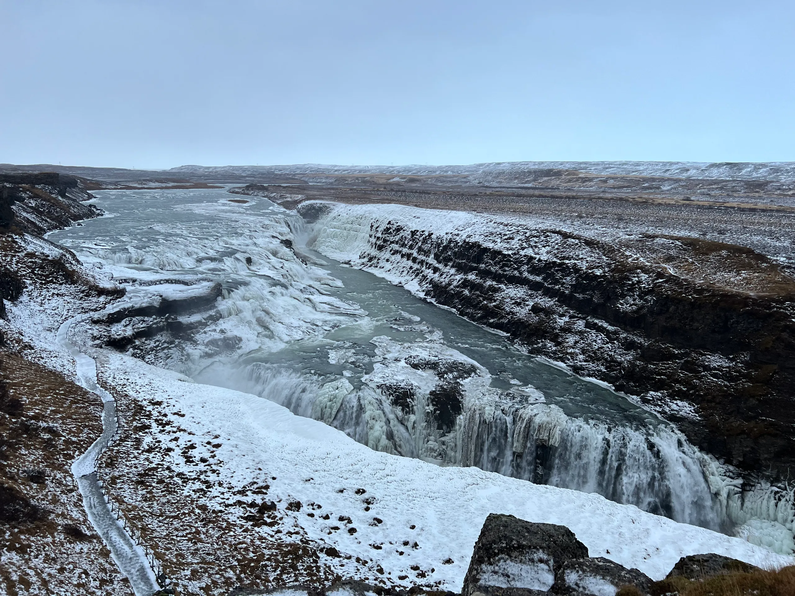 Gullfoss waterfall flowing through a gorge edged with snow and ice.