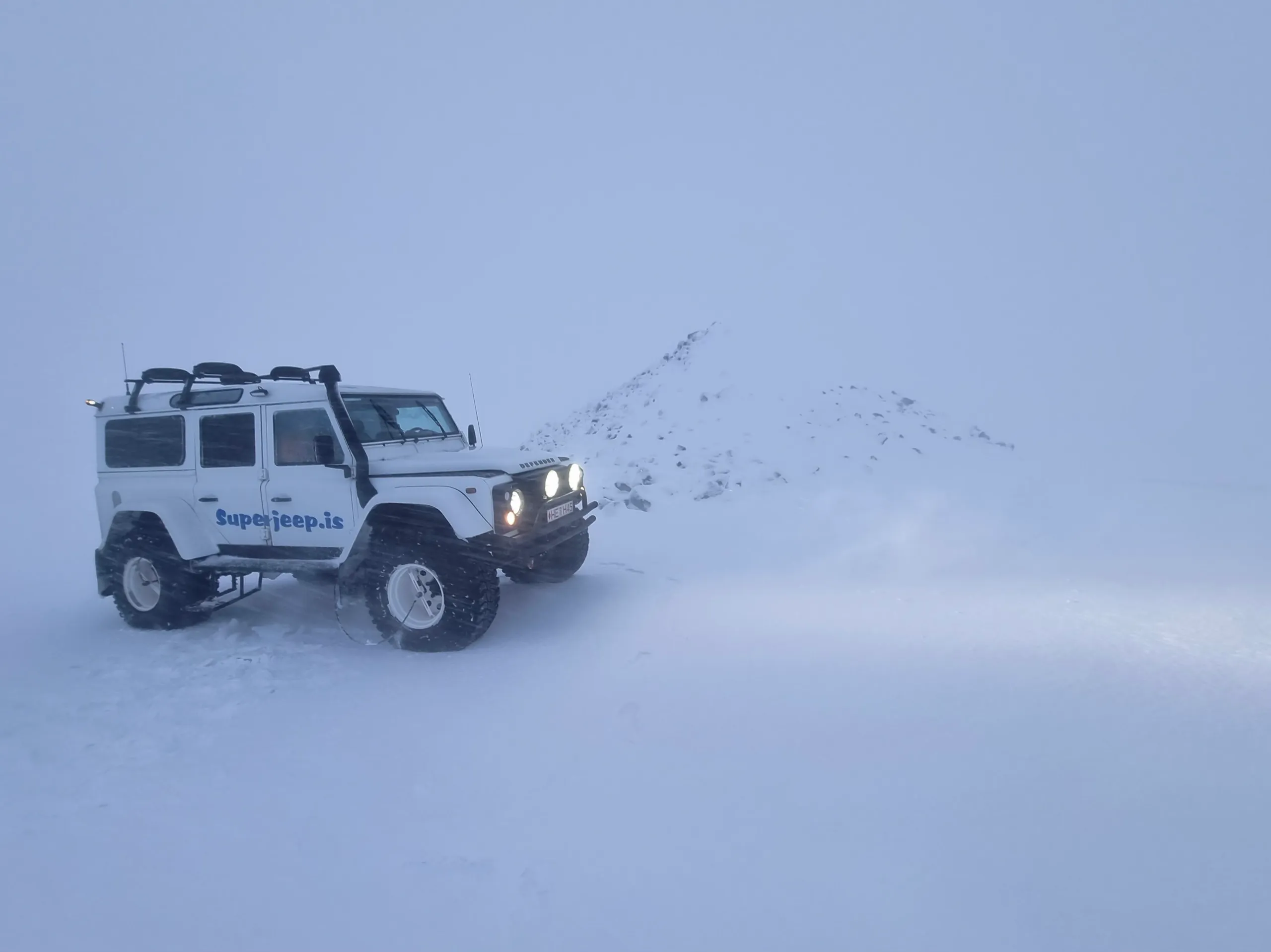 A large excursion vehicle in blowing snow on an Iceland winter outing.