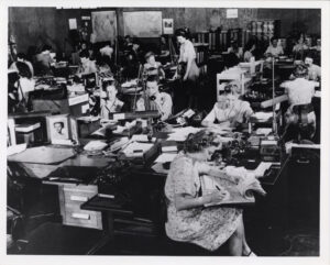 Women working at rows of desks in a crowded cryptologic office at Arlington Hall, Virginia, circa 1943.