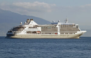 Silversea’s Silver Dawn cruise ship off Sorrento, Italy, with mountains behind it.