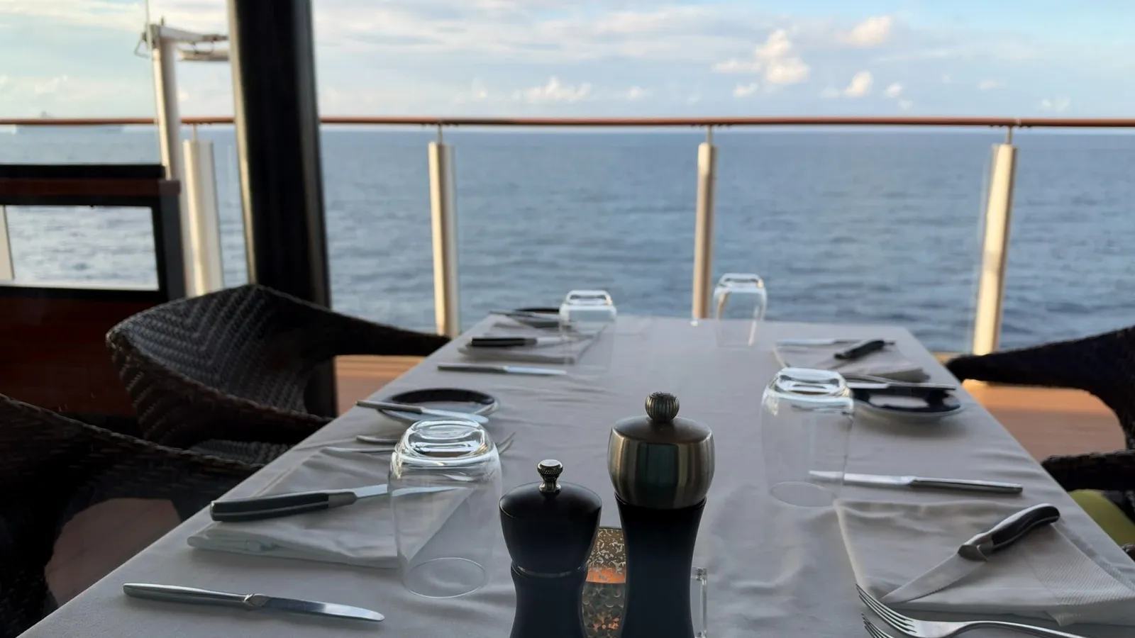 A table set for dinner beside the sea on Norwegian Getaway’s Waterfront.