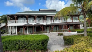 Garden path, clipped hedges and a two-storey building with white veranda railings and palms at Four Seasons Nevis.