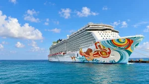 Norwegian Getaway docked at Great Stirrup Cay, with its colorful hull reflected in the water.