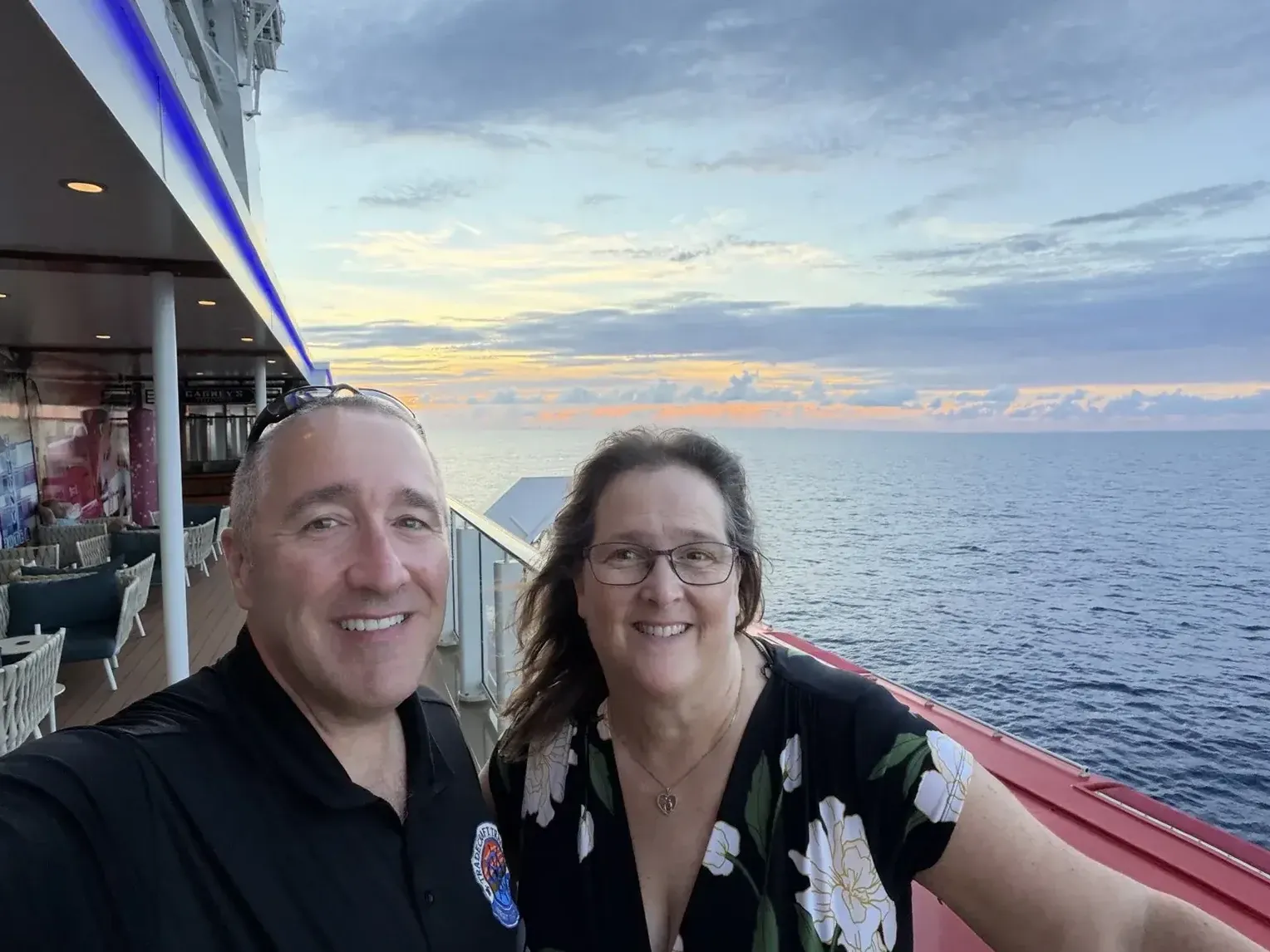 Jack and his wife on an outdoor promenade of Norwegian Getaway at sunset.
